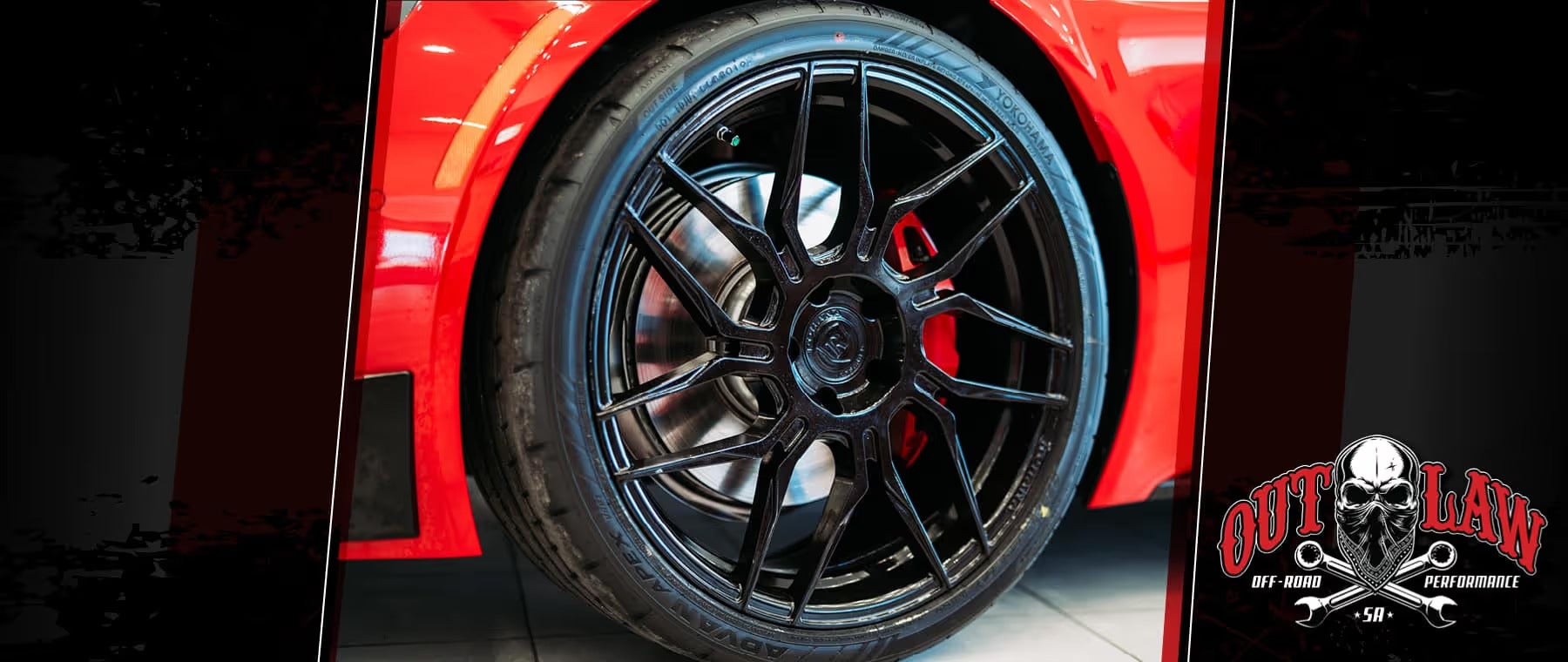 Close-up of a black multi-spoke custom wheel and low-profile tire on a red vehicle, displayed at Outlaw Off-Road Performance in San Antonio, Texas.